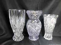Three clear lead crystal vases of varying sizes displayed against a black background showing their shape and cut patterns.
