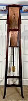 Full front view of wooden floor clock with copper-tone metal dial and black hands