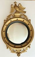 Front view of the Federal style convex mirror with gilt frame and carved eagle topper, showing overall shape and design.
