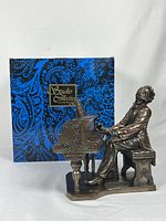 Photo of bronze-colored figurine of Frederic Chopin seated at an ornate piano with box in background showing the Studio Collectibles logo.