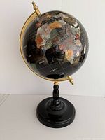 Full frontal view of the black globe mounted on black wood base with gold-tone meridian