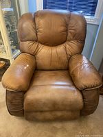 Front view of brown leather recliner showing overall shape and condition