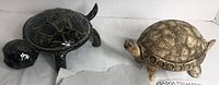 Two ceramic turtle figurines side by side, showing the full bodies and different finishes.