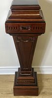 Front view of mahogany Adam style carved pedestal plant stand showing shape and carved floral accents.