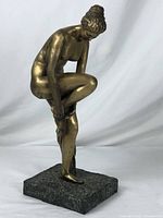 Front right three-quarter view of the nude female figure on a square textured stone base