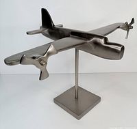 Front angle view of gun metal finish metal airplane on stand, showing propellers on wings and sleek design.