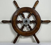 Front view of the wooden nautical ship steering wheel showing six handles and metal center hub.