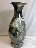 Front and angled views of a polished marble urn shaped vase showing veined black, white, and grey patterning and smooth polished surface.
