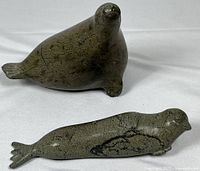 Two soapstone seal sculptures, one upright and one lying down, showing size and condition