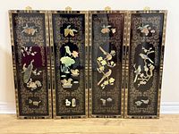 Front view of all four carved jade lacquer panels side by side showing detailed jade inlays of birds and flowers with gold ornamental borders