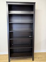 Full front view of the dark brown shelving unit with six shelves, showing the height and overall structure.