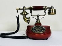 Front and side view of Southern Telecon replica telephone showing wooden base, rotary dial with brass details, and metal handset with wooden grip.