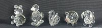Photo showing all five Swarovski crystal figurines together: bear, duck, swan, pig, and dog in a row.