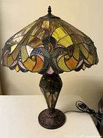 Front view of Tiffany-style table lamp showing multicolored stained glass shade and ornate resin base
