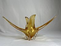 Front view of vintage amber chalet style glass centerpiece sculpture with long swept wings and clear glass base.