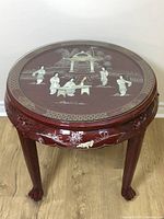 Front angled view of the round vintage Chinese lacquered table showing the top inlay and carved legs.