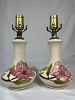 Two William Moorcroft pink magnolia pottery table lamps shown side by side.