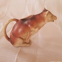 Left side view of the ceramic cow milk pitcher showing handle and body details.