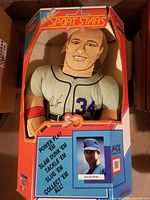 Front view of the plush doll in original box with colorful graphics and Nolan Ryan image
