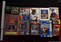 Photo showing multiple baseball memorabilia books, magazines, posters, boxed items including a Babe Ruth commemorative baseball and Beckett magazine.