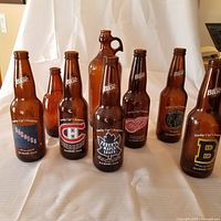 All 8 brown glass bottles arranged, including 6 NHL themed Labatt Original bottles, an antique Javex jug bottle, and a Carling stubby.