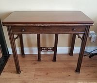 Closed view of the walnut console table with visible carved legs and single drawer with wooden knobs.
