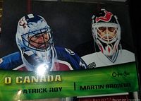 Close-up of a large hockey card or poster with Martin Brodeur and Patrick Roy in goalie masks representing Team Canada and New Jersey Devils/Colorado Avalanche.