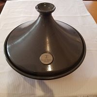Top view of dark brown ceramic tagine with Emile Henry logo on lid.