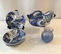 Group photo showing six blue and white Ridgeway Meadowsweet dishes with countryside scenes, the bird-shaped blue and white teapot, and the small blue handblown glass vase.
