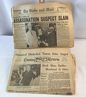 Two aged newspapers displayed, with visible headlines about assassination suspect slain and related JFK news