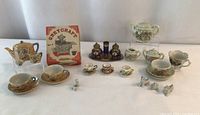 Full lot of miniature tea set items, puppy figurines, brass salt and pepper set, and boxed cast iron cookware