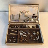 First image shows an open vintage jewellery box containing multiple compartments filled with cufflinks of various designs and materials.