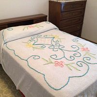 Full view of vintage chenille bedspread on double bed, showing floral and scrollwork pattern, scalloped edge, and bedspread spread over bed.