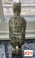 Full frontal view of the carved stone figure on windowsill under natural light
