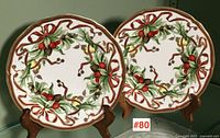 Two Tiffany Holiday plates displayed front-on on wooden stands
