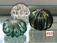 Three paperweights arranged side by side on glass shelf.