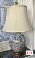 Full view of lamp showing vase-shaped ceramic base, brass and wood plinth, fabric shade
