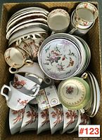 Basket containing assorted cups, saucers, bowls and sugar bowl with lid, top-down view