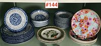 Full assortment showing stacks of the various plates in the lot, distinct patterns included: blue and white florals, beige bird motif, and colorful floral prints.