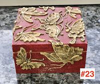 Top view of square soapstone box showing carved butterflies and leaves on red background