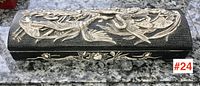 Top view of black soapstone box with raised cream-colored carving featuring birds and flowers.