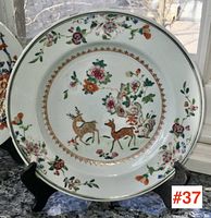 Overall front view of the plate on display stand showing full decoration and gilt rim