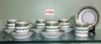 Six cups and six saucers arranged side by side on glass shelf
