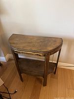 Front view of the half moon wooden table showing the top surface and lower shelf.