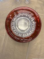 Top view of a ruby-rimmed plate showing the clear textured center with raised ovals and smooth middle circle.
