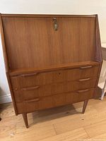 Front view of letter desk showing drop-front closed, three lower drawers with integrated handles and tapered legs