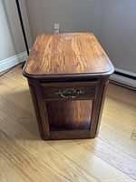 Front view of the end table showing the top surface, decorative drawer handle, and sturdy legs.