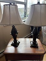 Set of two pineapple design table lamps with cream fabric shades on a wooden end table.