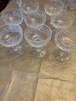 Front and angled view of eight cut crystal coupe glasses arranged on tabletop.