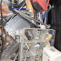 Mixed metal wire brush, plastic organizer with screws and hardware, brass fittings, and metal parts in a bin